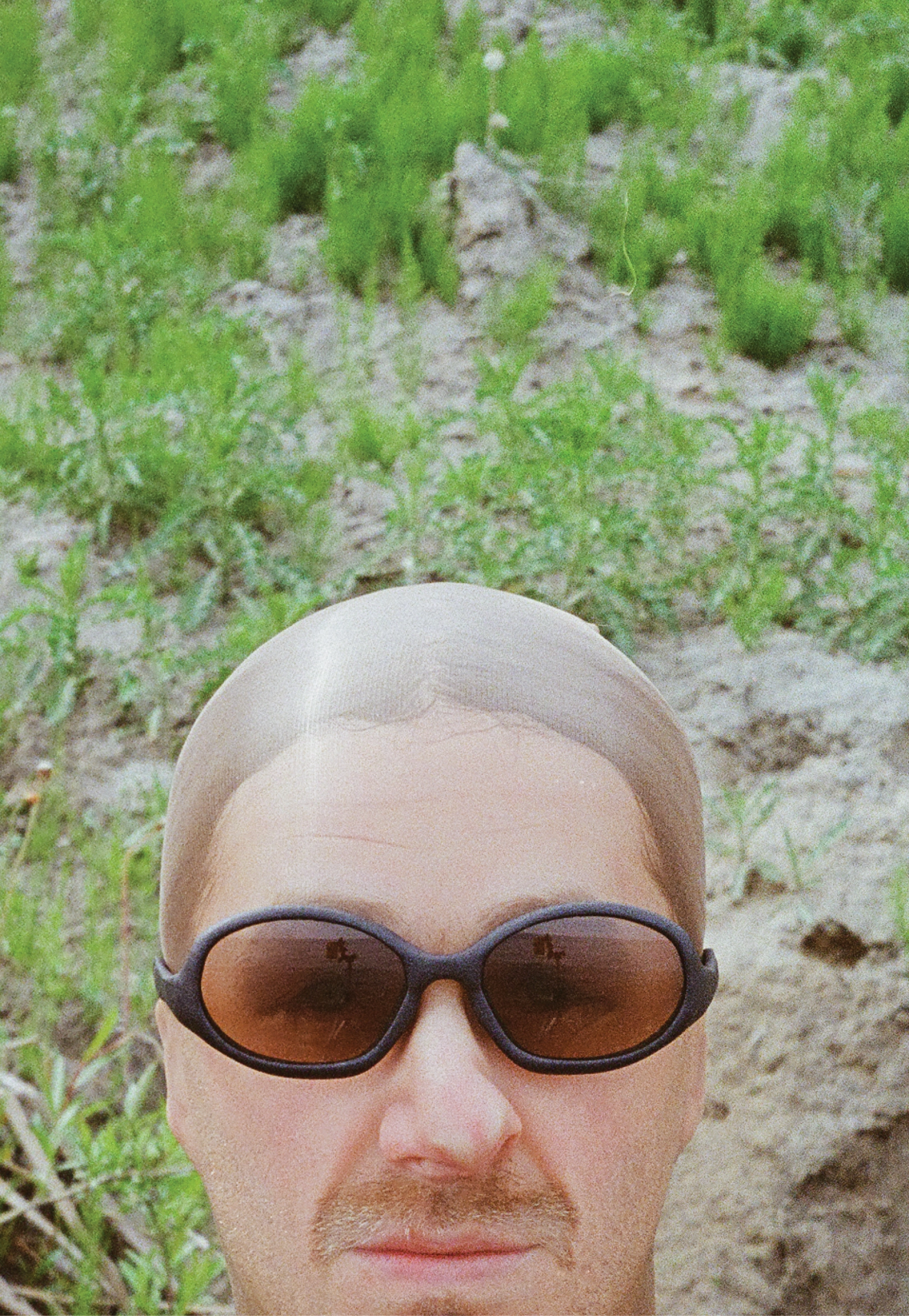 3D render of a bald model wearing black sunglasses with transparent grey lenses